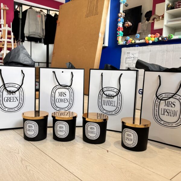 Four black candles with wooden lids labelled 'Mrs. Green' and other family names.