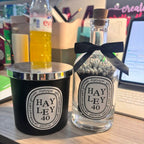 A candle and diffuser set with 'HAYLEY 40' labels on a desk.