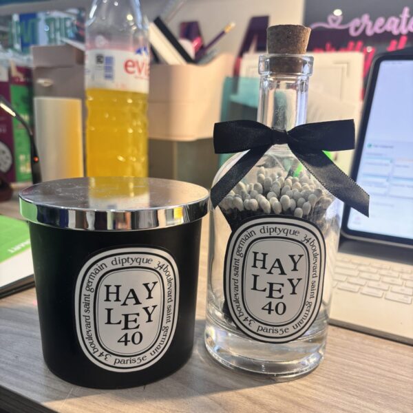 A candle and diffuser set with 'HAYLEY 40' labels on a desk.