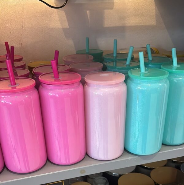 Colourful cold cups with straws on a shelf.