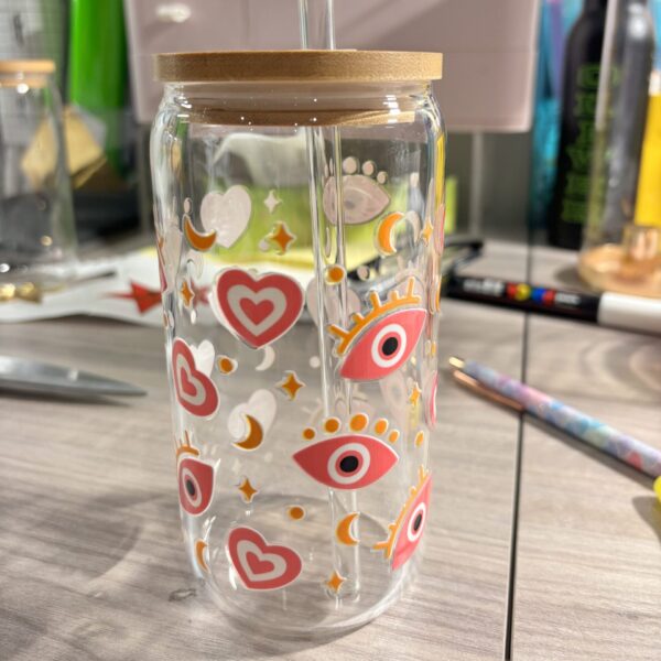 Clear cold cup with colourful designs on a wooden surface.