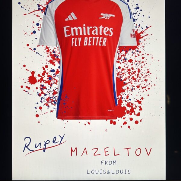Red and white Arsenal football shirt gift with Emirates branding on a white background with red and blue splashes.