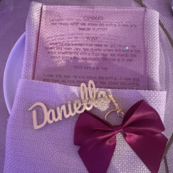 Purple bow with a gold acrylic name tag on a matching background