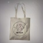 Beige tote bag with 'MYLA' logo on a light grey background