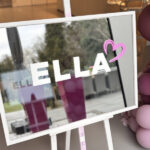 Bespoke mirror white-framed with 'ELLA' and a heart sticker, surrounded by pink balloons.