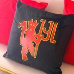 Black logo pillow with red and yellow design on a red cushion