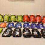 Row of colourful boot bags with visible branding on a white surface.