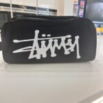 Black boot bag with white logo on a reflective surface