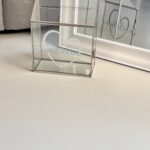 Clear gift card box on a white wall with 'Natalia' personalised branding.
