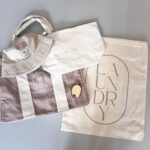 Collection of personalised bags including a hat, tote bag, and laundry bag on a grey background