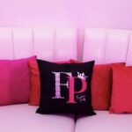 Decorative logo pillows with 'FP' logo on a pink couch