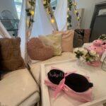 Decorative personalised pillow setup with pillows, a coffee table, sleep mask and fairy lights in a room.