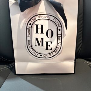 Gift bag with 'HOME' and personalized text on a black background