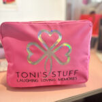 Pink washbag with a four-leaf clover design and 'TONI'S STUFF' text on a blurred background