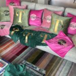 Grey sofa with decorative logo pillows featuring initials and patterns in a room.