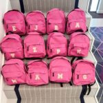 Multiple pink  backpacks with letters on a staircase