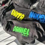 Black hoodies with personalised names and dates on a light background