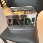 Collection of colourful 'JAYD' branded stickers on a gift box on a black chair