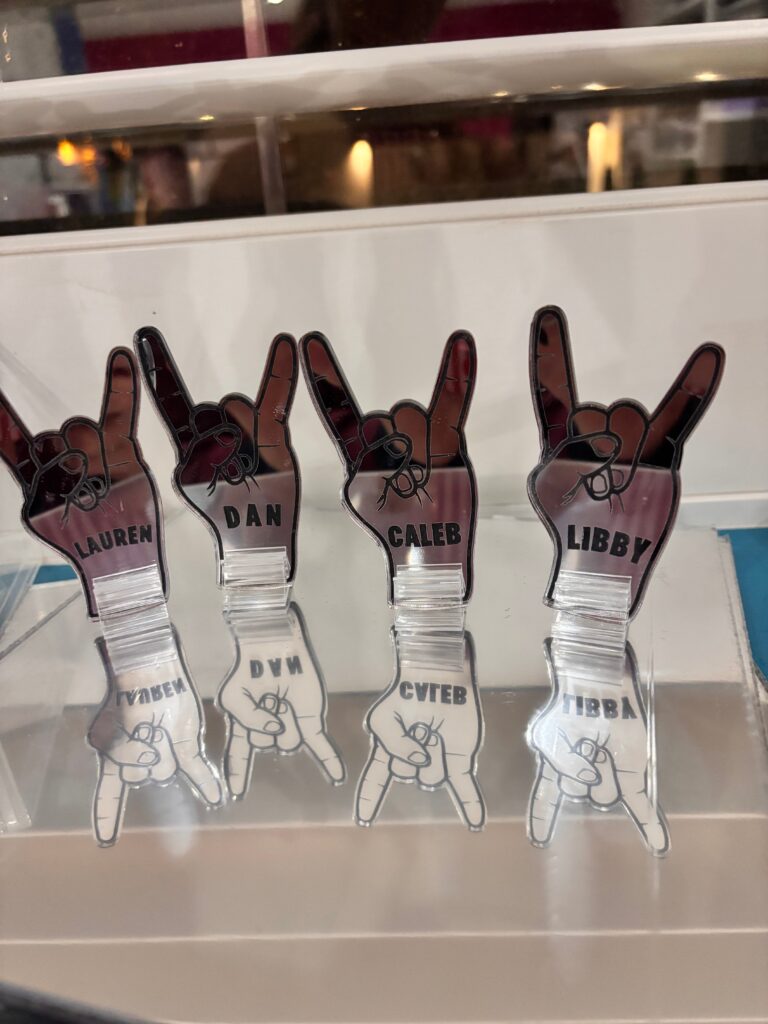 Set of personalized hand-shaped acrylic place names on a reflective surface.