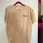 Beige event t-shirt with 'Chloe' branding on a white surface
