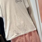 White t-shirt and pink pants pyjamas with 'Olivia's' logo on a hanger.