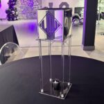 Clear acrylic gift card box podium with decorative elements in a room with purple lighting