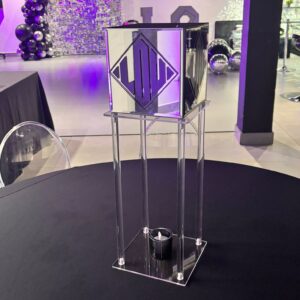 Clear acrylic gift card box podium with decorative elements in a room with purple lighting