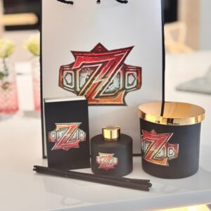 Diffuser with gold accents and a decorative bag featuring a logo and matchbox gift set