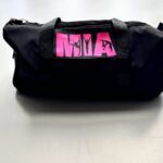 Black washbag with pink logo on a tiled floor