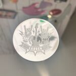Silver place name with a design on a reflective surface