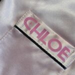 Label with 'CHLOE' printed on a beige pyjama front pocket