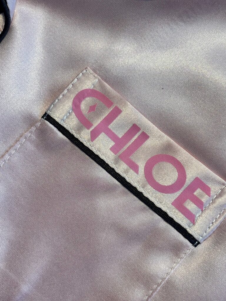 Label with 'CHLOE' printed on a beige pyjama front pocket