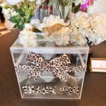 Leopard print ribbon on a clear gift card box with 'THANK YOU' text, surrounded by flowers.