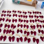 Maroon bow keyrings with names on a white surface