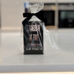 Match box holder sleeve in black with silver customised with 'Shabbat at the Espinozas' text on a kitchen counter