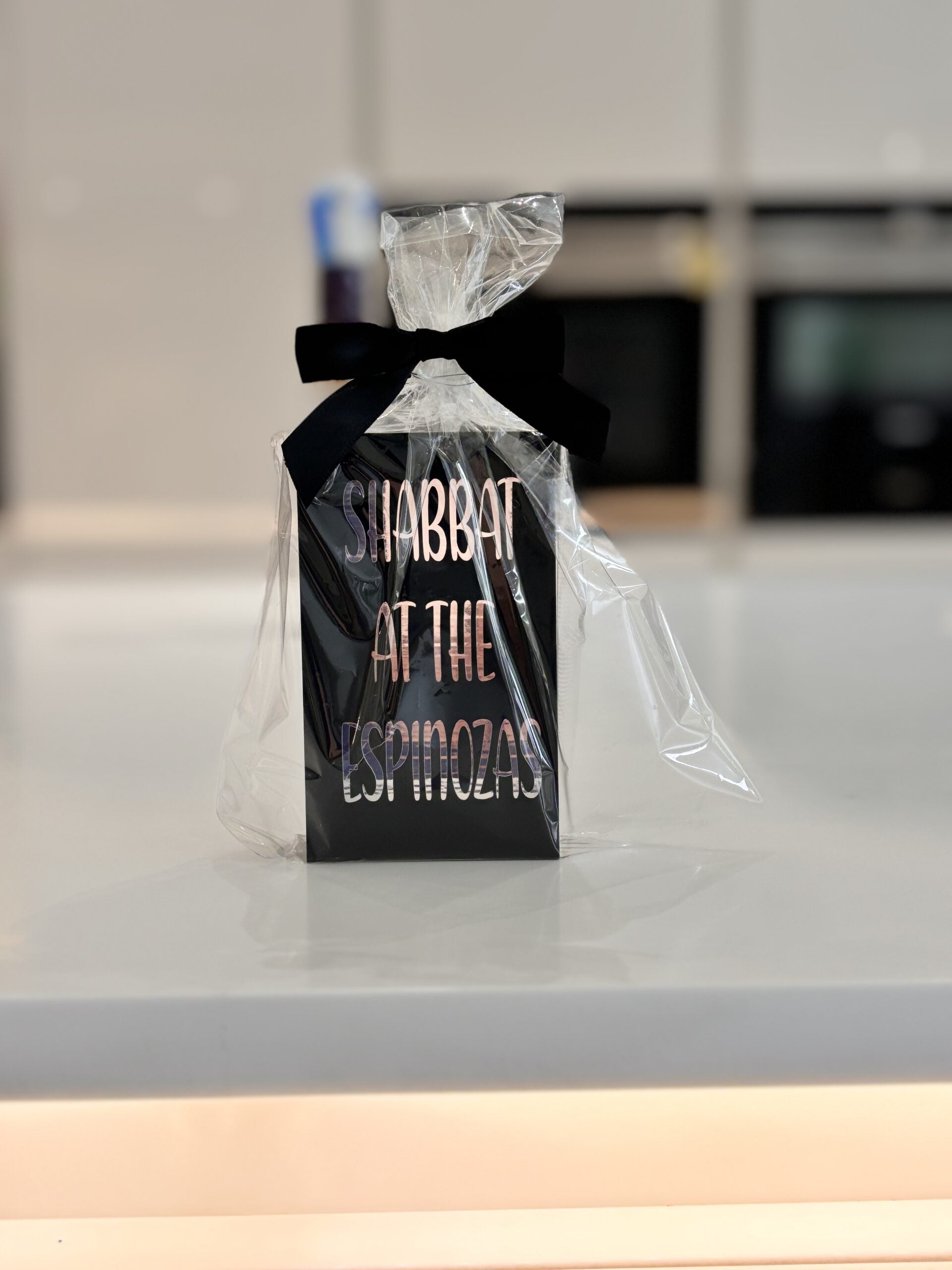 Match box holder sleeve in black with silver customised with 'Shabbat at the Espinozas' text on a kitchen counter