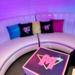 Neon table top sign with a logo with personalised logo pillows in the background