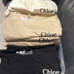 Personalised Chloe event t-shirts in a clear plastic container on a light-coloured surface