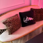 Pink chair with leopard print logo pillows and a black pillow with pink text.