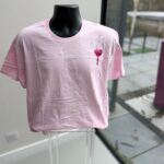 Pink event t-shirt with a heart design on a mannequin against a glass door background