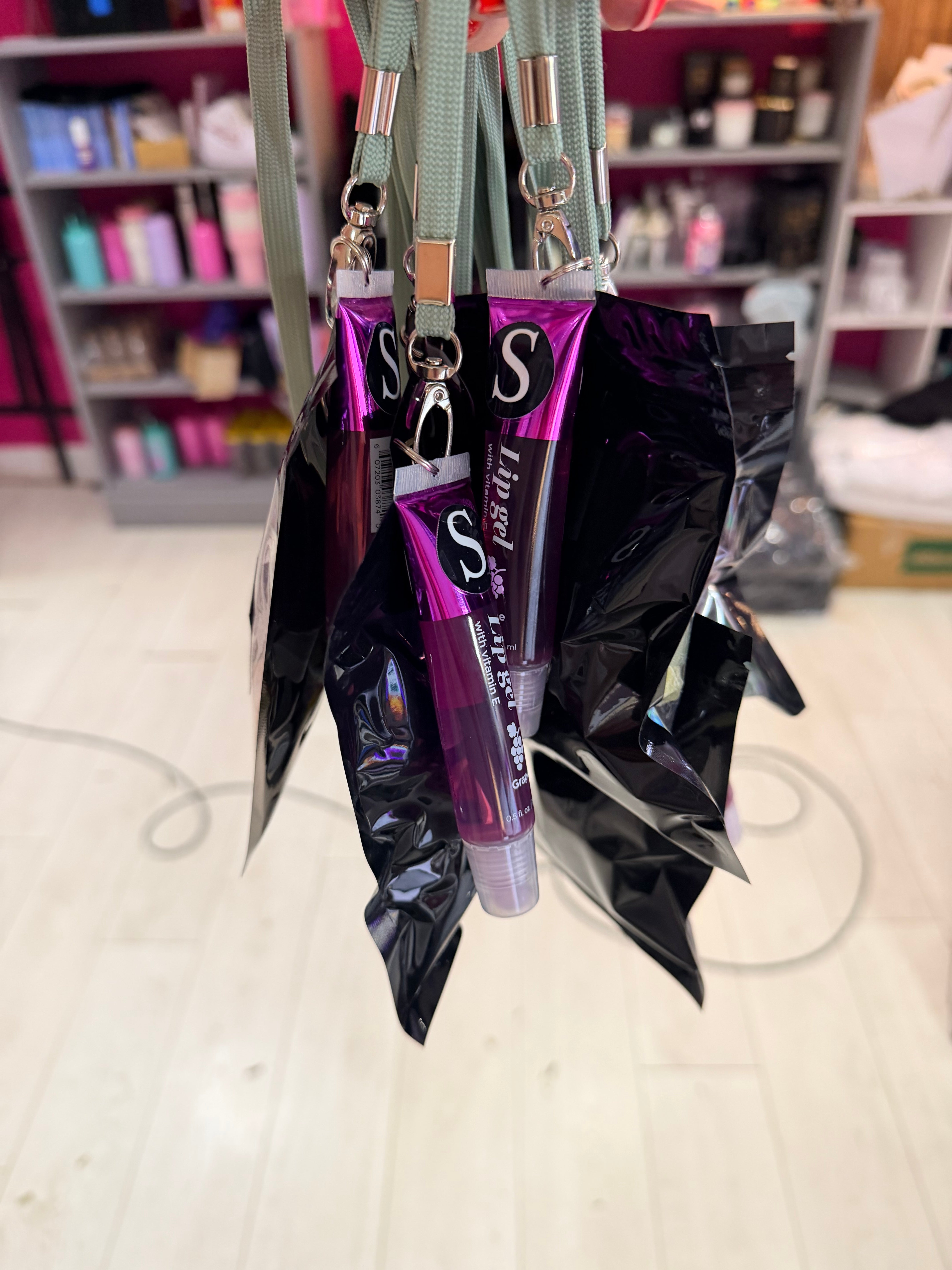 Purple lip gloss keyrings with silver cap on a reflective surface, blurred background