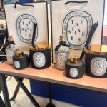 Set of personalised candle, match bottle and diffuser sets with decorative boxes on a stand