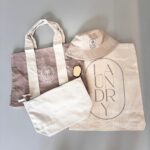 Set of three personalised tote bags including a tote, a hat, and a laundry bag on a grey background