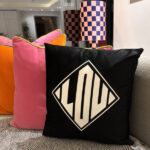 Silk pillow case with a black pillow featuring a geometric design on a couch.