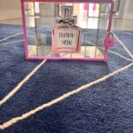 Small perfume bottle design with 'THANK YOU' text in a decorative gift card box on a textured surface.