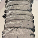 Stack of black sleep masks with names printed on them against a white background.
