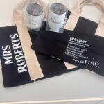 Teacher-themed tote bags with personalised names and definitions on a light surface.