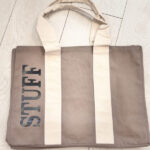 Tote bag with 'STUFF' printed on it on a light wooden floor.