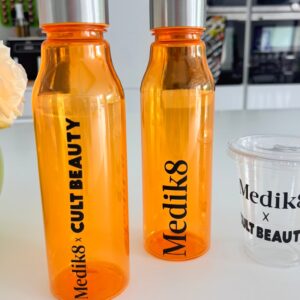 Two orange sports insulated water bottles with silver lids on a white surface, featuring 'Medik8' branding.