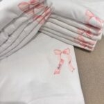 White event t-shirts with pink bows on a neutral background